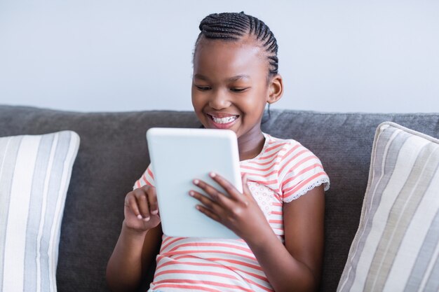 Girl sitting on sofa using digital tablet