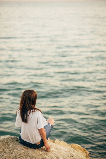 海岸の石の上に座っている女の子