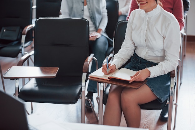 Girl in skirt is smiling. Group of people at business conference in modern classroom at daytime