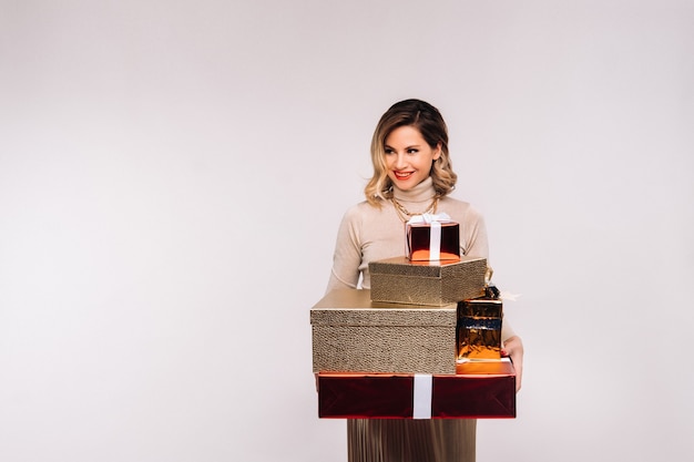 A girl in a skirt and jacket with a lot of gifts in her hands on a white background