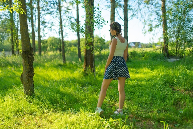 A girl in a skirt and Tshirt walks through the woods