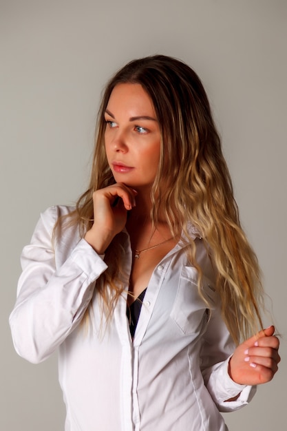 Девушка славянской внешности в белой рубашке на сером фоне