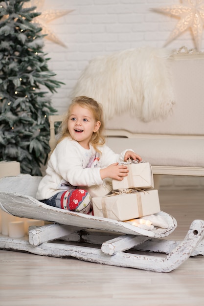 Ragazza che sledding con il contenitore di regalo di natale.