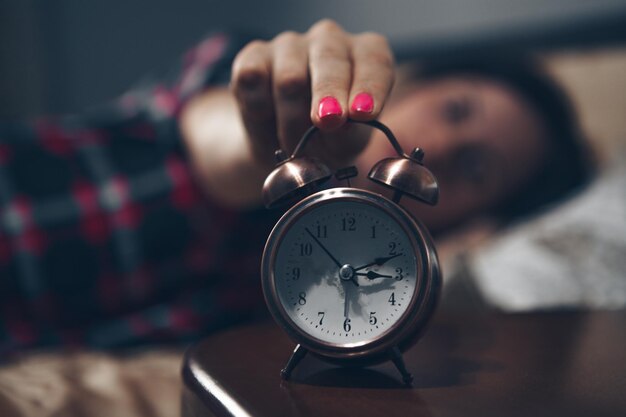 Photo girl sleeping in bed set alarm clock