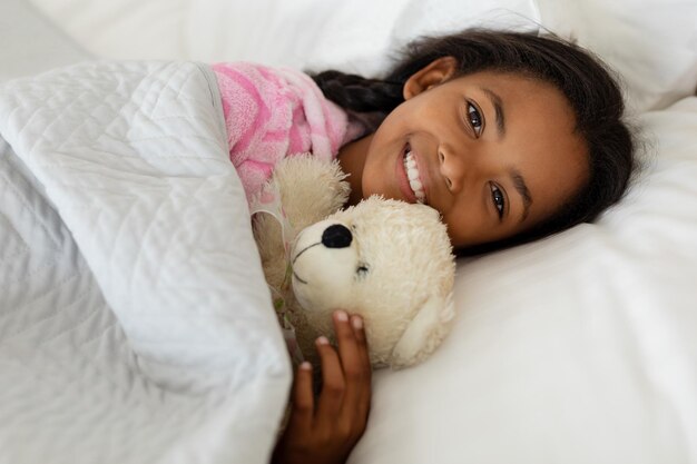 Girl sleeping with teddy bear in bed in bedroom at home