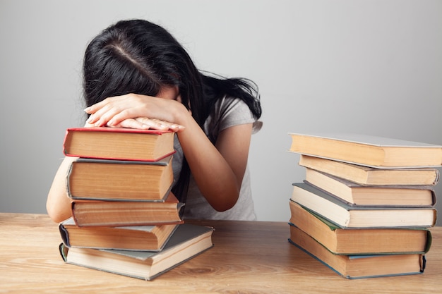 The girl sleeps on the table next to the books