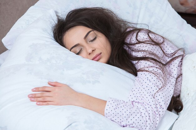 Girl sleeps in a white bed at home