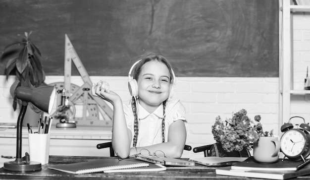 Photo girl small child eating apple fruit snack between lessons schoolgirl sit desk chalkboard background kid student in school healthy lifestyle school life concept modern childhood school break