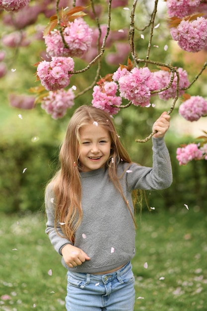 A girl smelling a branch of a cherry blossom tree