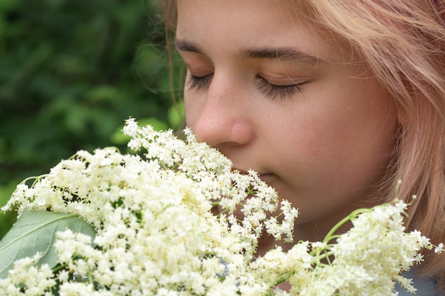 Ragazza odorando fiori di sambuco in giardino