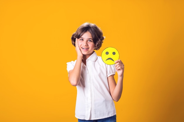 Girl smile and holds sad emoticon Mental health psychology and childrens emotions concept