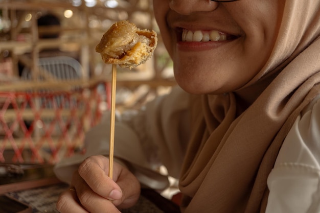 The girl smile when eating the traditional snack Tahu Walik.