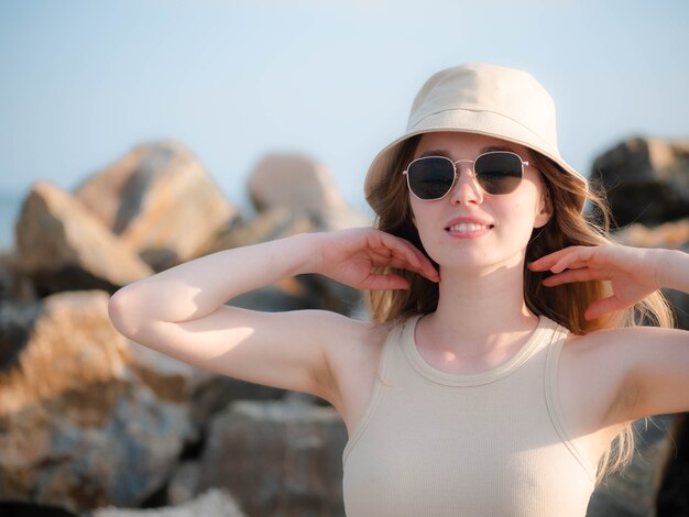 The girl smiles against the background of stones and touches her hair