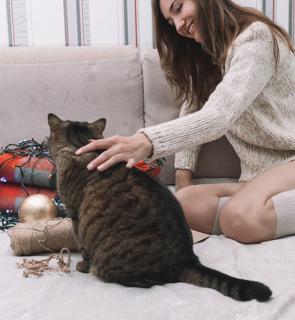 写真 女の子は笑顔で猫を撫で、周りのクリスマスの飾り