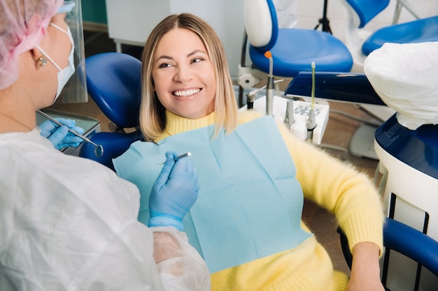 The girl smiles at the dentist and looks at her.