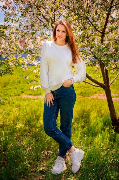 Девушка улыбается в саду с цветущими вишнями