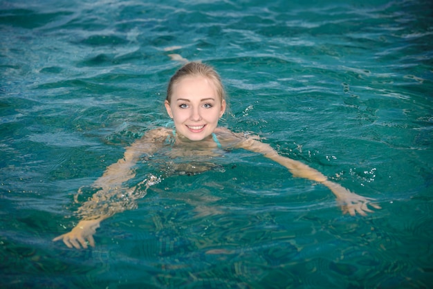 The girl smiles while swimming in the pool.