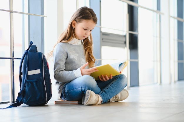 Girl smiling Beautiful schoolgirl smiling while sitting near window and reading book