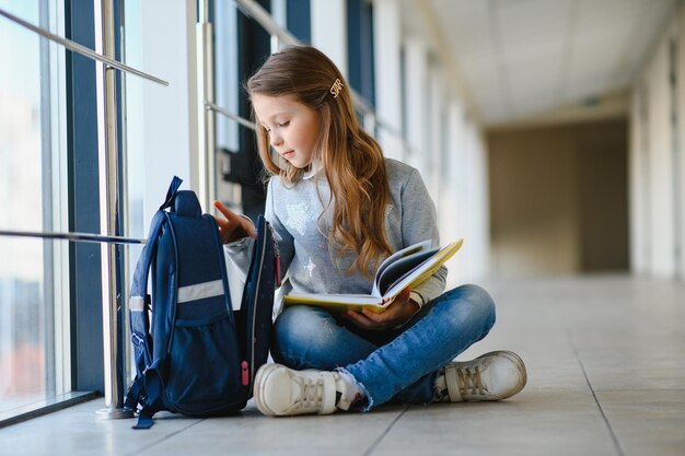 Girl smiling Beautiful schoolgirl smiling while sitting near window and reading book