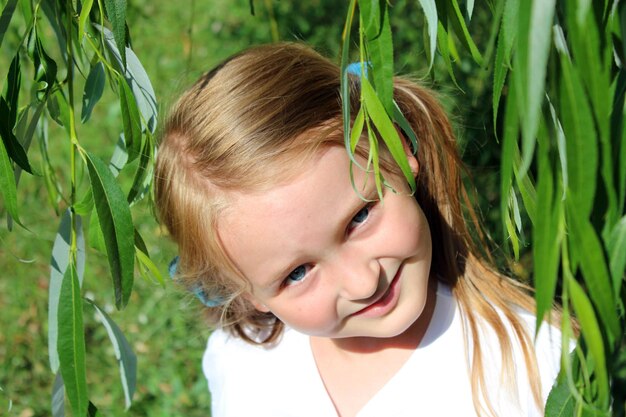 Girl smiling besides the leaves of willow