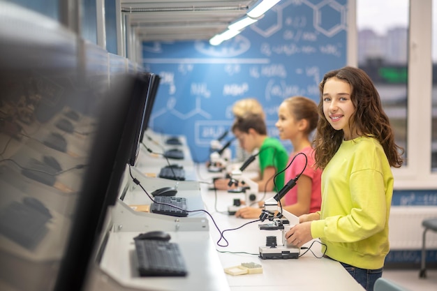 Girl smiling at camera standing near microscope