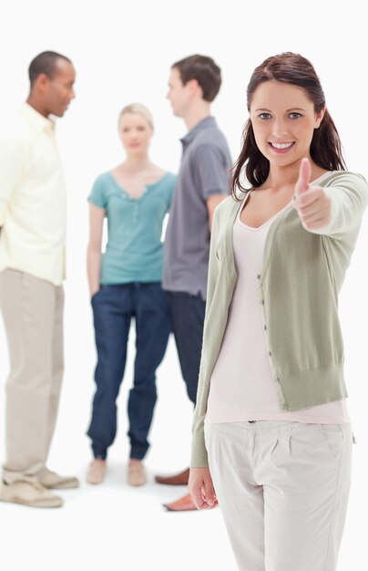 Girl smiling and giving the thumbs-up with friends