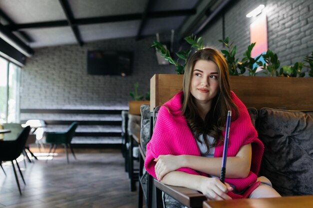 The girl smokes a hookah Hookah in a restaurant Woman smokes a hookah and sits on a chair The girl is sitting on a sofa in a cafe