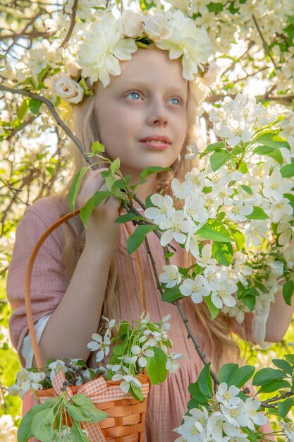 りんごの木の開花の真っ只中に、女の子が美しい白いりんごの木の春を嗅ぎます。