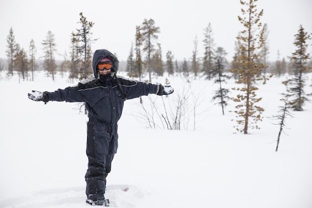 A girl in snow overalls and orange glasses plays with the snow\
in the tundra of lapland