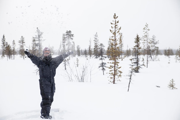 A girl in snow overalls plays with the snow on the lapland\
tundra