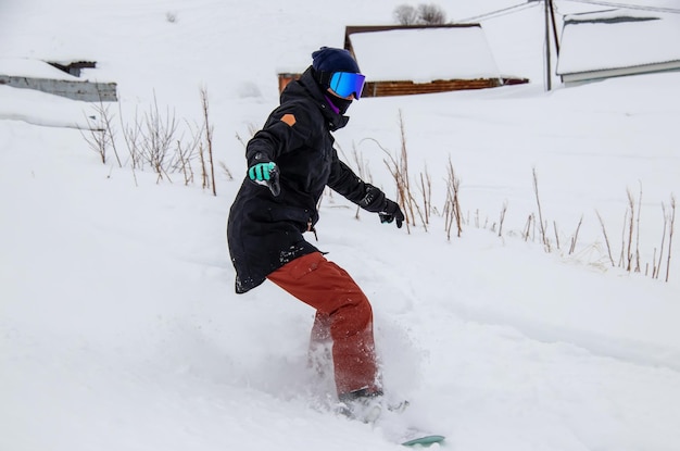 A girl on a snowboard rides down the side of the mountain