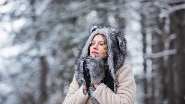 Girl in snowy forest faux fur animal hat perfect for fantasy\
theme heartwarming concept animal care winter themed portrait cosy\
outfit woman wear wolf hat animal rights wild life symbol