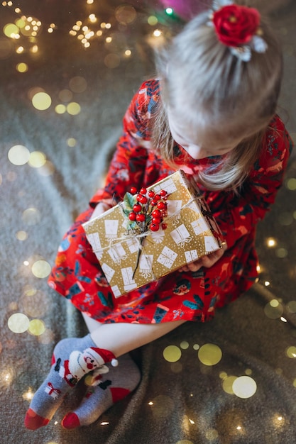 A girl sorts out gifts against the background of a Christmas tree