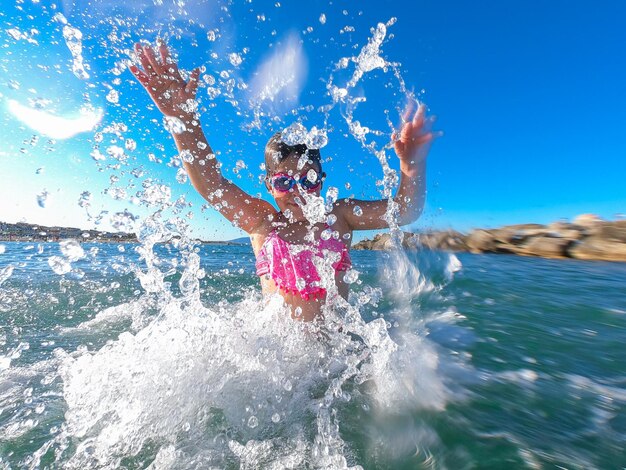 Photo girl splashing water in sea against sky