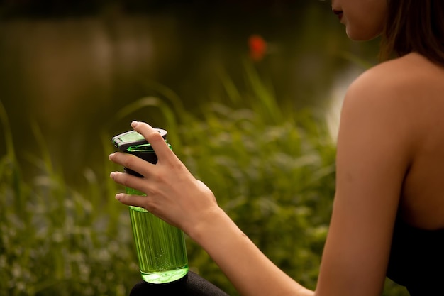 a girl in a sports uniform holds a bottle in her hand, a girl drinks water from a bottle