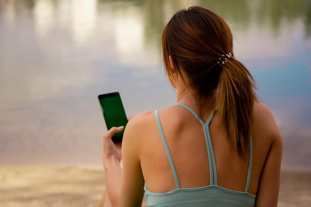 a girl in a sports uniform holds a phone in her hands, dressed in a green tracksuit top and bicycle