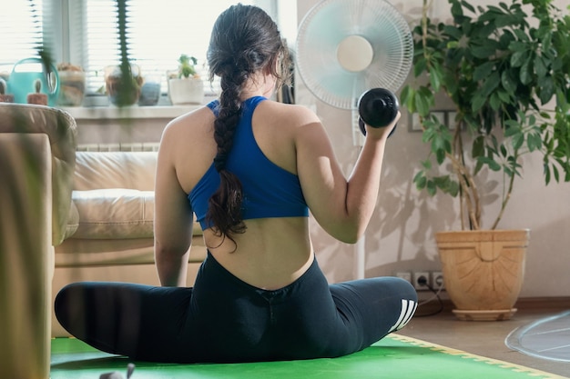 Girl in sportswear doing fitness at home sitting on the\
floor