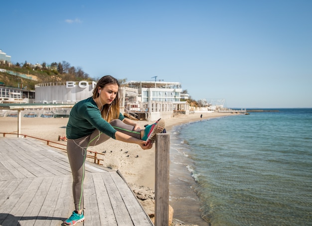 Girl in sportswear doing stretching by the sea