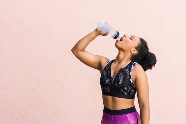 Girl in sportswear drinks water after training