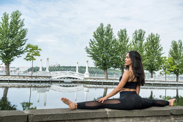 Girl in sportswear go in for sports and healthy lifestyle doing twine by lake, nature