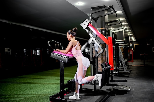 A girl in sportswear in a professional gym works out with fitness equipment.