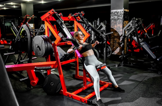 A girl in sportswear in a professional gym works out with fitness equipment