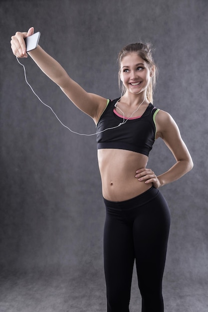 Girl in sportswear smiling and taking selfie