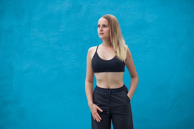 Girl in sporty black top on blue wall