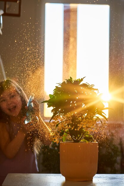 Foto una ragazza spruzza fiori da una bottiglia di spray nei raggi del sole primaverile del mattino