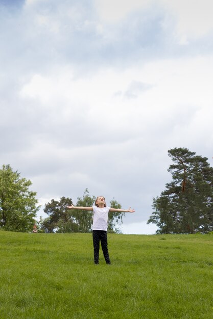 The girl spread her arms to the sides and closed her eyes against the background of the sky and nature. Camping concept, digital detox, enjoying nature and summer