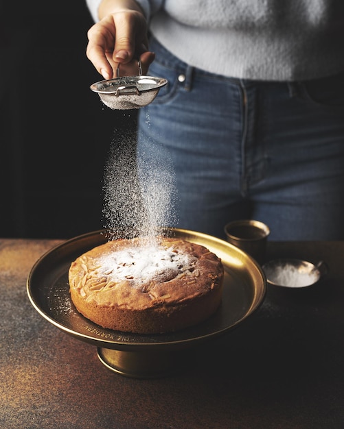 the girl sprinkles the cake with powdered sugar