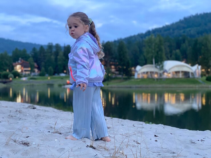 Photo girl standing by lake against trees
