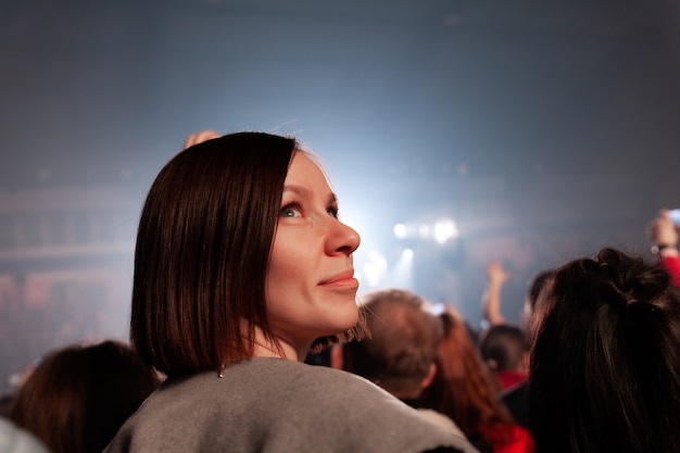 Photo girl standing at concert on background of people crowd and neon light