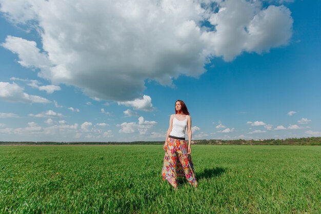 Girl standing in a green field of blue sky with clouds Copy space